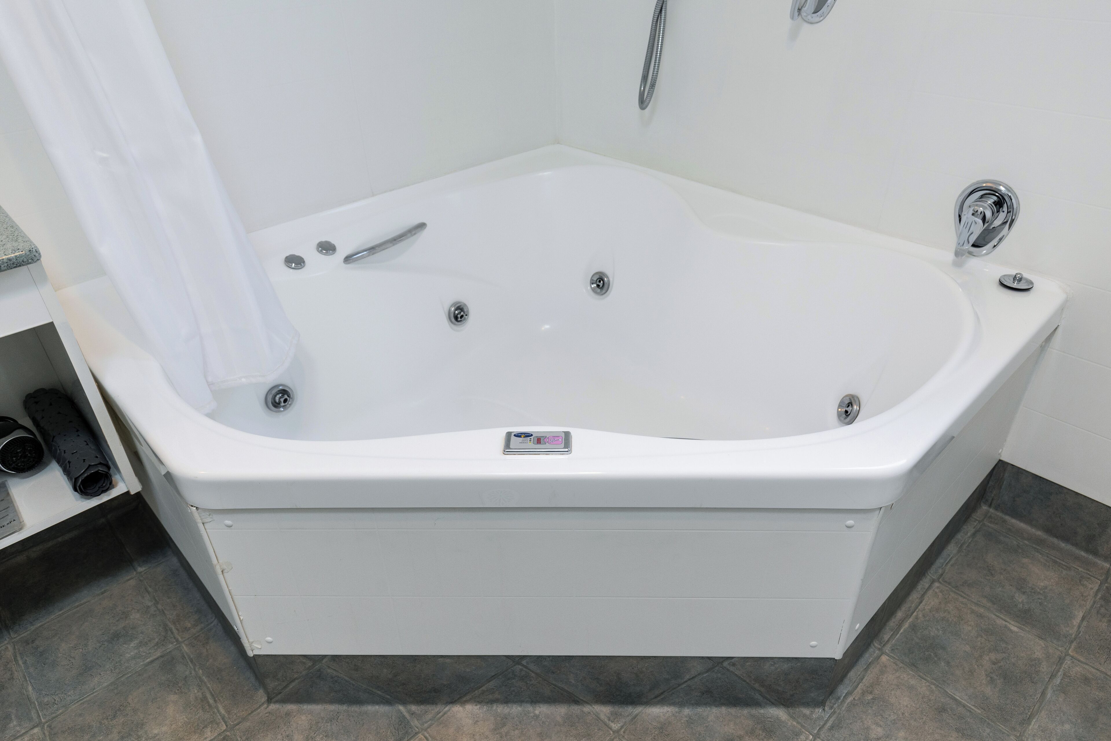 Un baño moderno con una bañera independiente, un cabezal de ducha y un panel de control en la bañera.