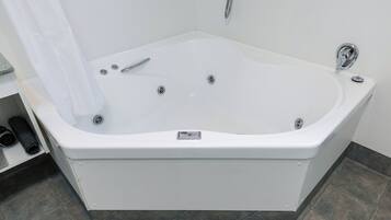 A modern bathroom with a freestanding bathtub, a showerhead, and a control panel on the tub.