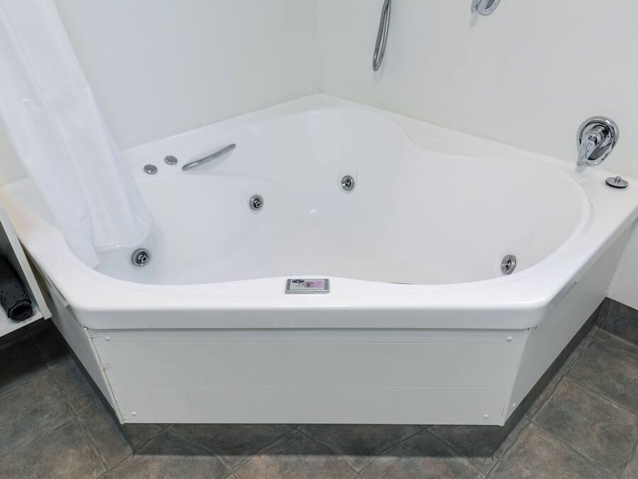 A modern bathroom with a freestanding bathtub, a showerhead, and a control panel on the tub.