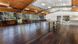 Un vaste espace intérieur doté de hauts plafonds, de parquets en bois et de grandes fenêtres offrant une vue sur l’extérieur.