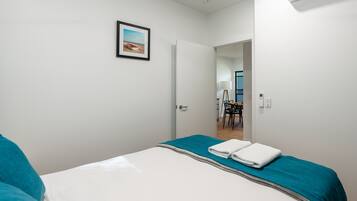 A hotel room with a bed, a door leading to a dining area, and an air conditioning unit.