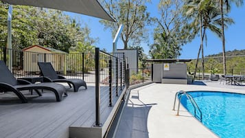 Una piscina al aire libre, sombrillas, tumbonas