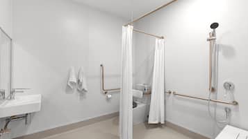 A modern bathroom with a white sink, a shower with a handheld showerhead, and a grab bar.