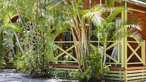 Un bâtiment en bois doté d’un porche, entouré de plantes tropicales.