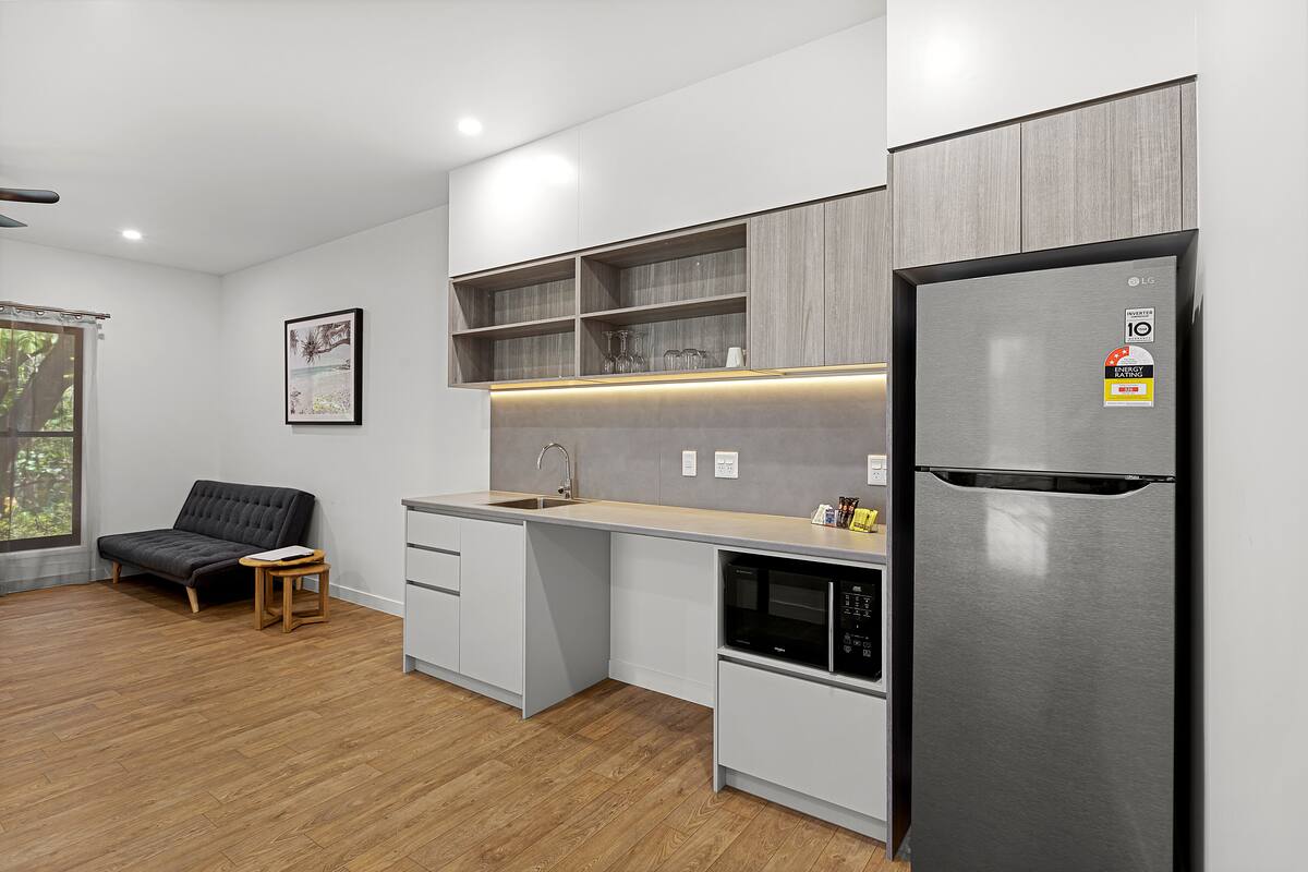 A modern kitchen with a built-in microwave, a refrigerator, and a wooden dining table.