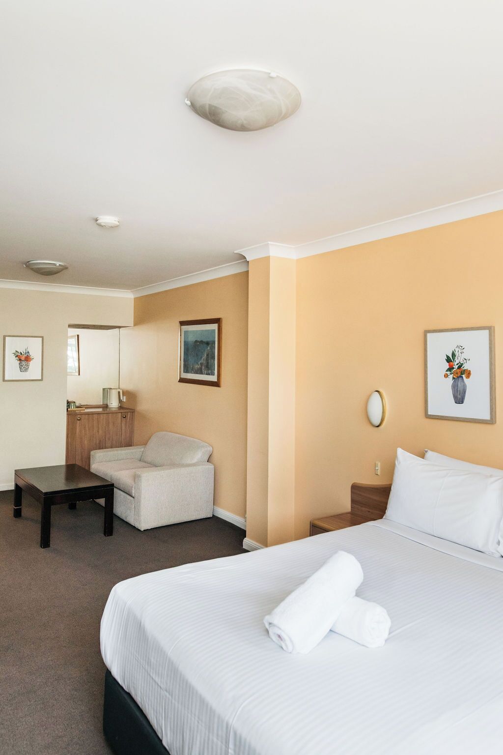 Una habitación de hotel con cama, sofá, una mesita, una mesilla de noche y un espejo.