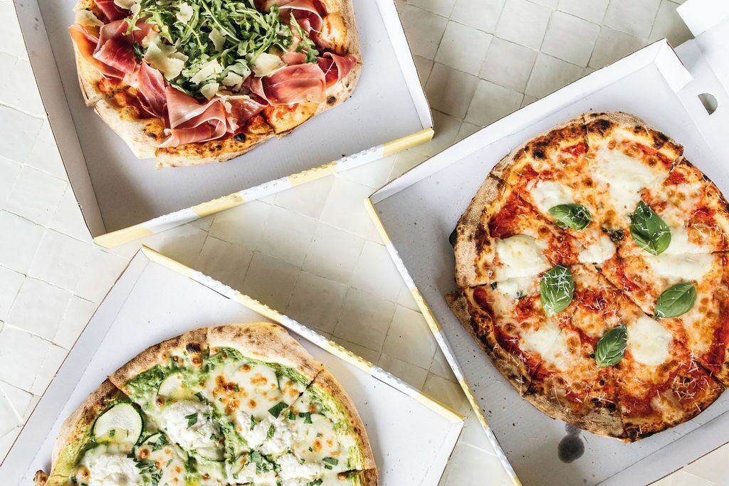 Drie pizza's in kartonnen dozen.