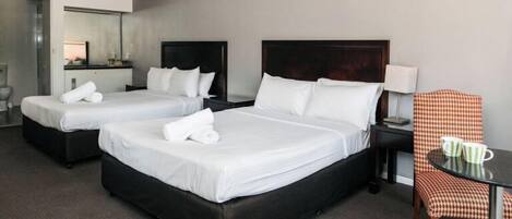 Una habitación de hotel con dos camas, una mesita pequeña con una silla y un espejo.
