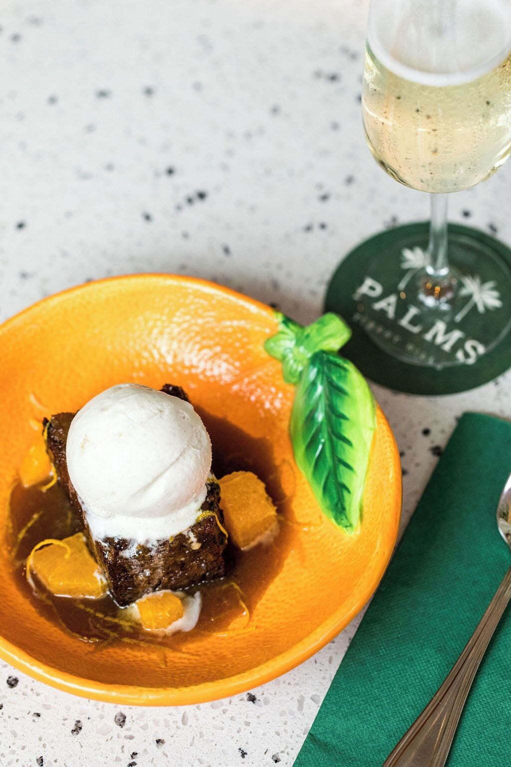 A dessert with a scoop of ice cream on top, served in a yellow bowl with a green napkin beside it.