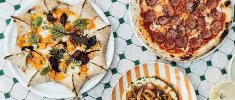 Una mesa con tres platos: una pizza, una ensalada y un plato de pasta.
