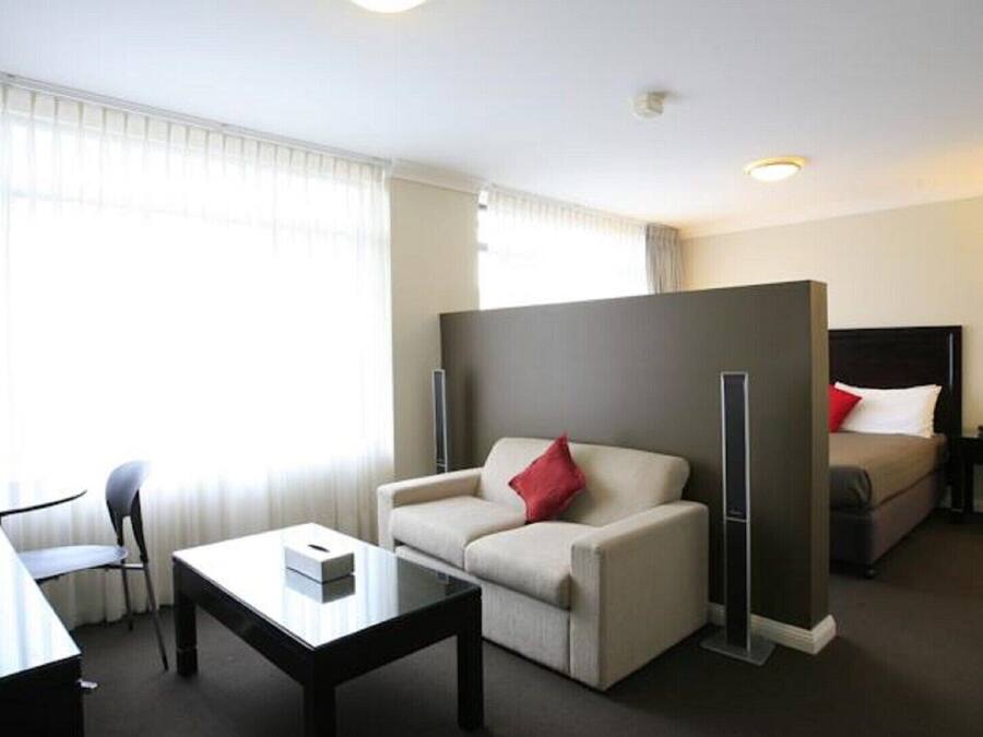 Een hotelkamer met een bank, een kleintje tafeltje, een bed en een bureau.