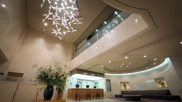 A spacious lobby with a reception desk, seating area, and a large vase of flowers. - Sendai Garden Palace (Sendai)