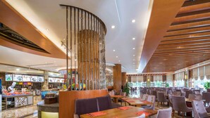 Un restaurante amplio con varias mesas y cabinas, una columna decorativa en el centro y vistas al área de la cocina.