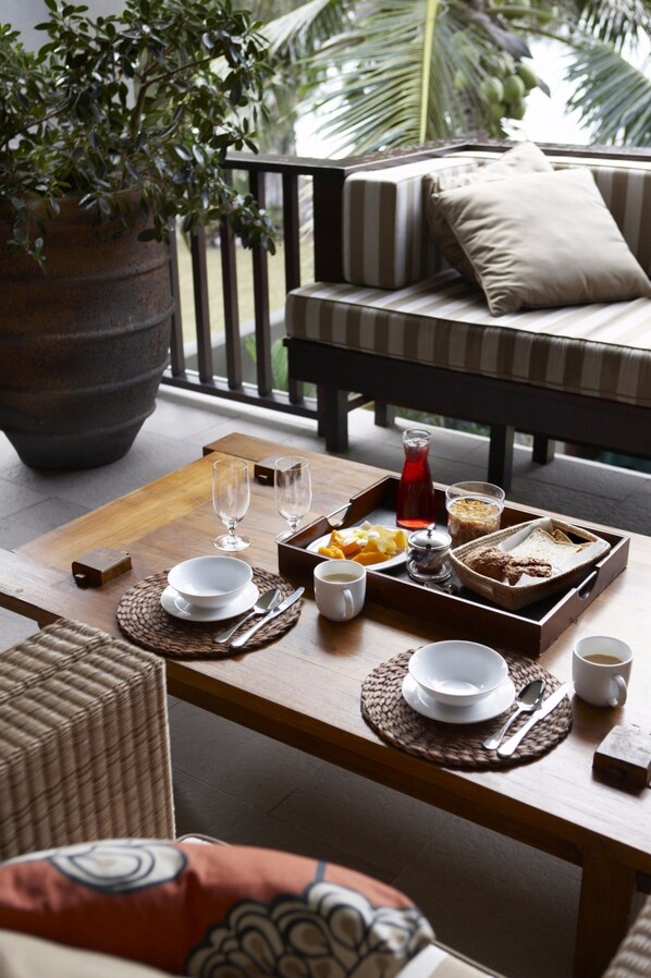 A dining area with a wooden table set for breakfast, including plates, glasses, and a tray with food and beverages. - Te Vakaroa Villas (Rarotonga)