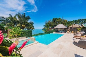 A swimming pool with a view of the sea, surrounded by palm trees and lounge chairs. - Te Vakaroa Villas (Rarotonga)