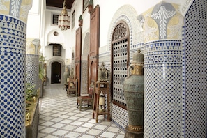 A narrow corridor with patterned tiles, wooden furniture, and ornate doors. - Riad El Yacout (Fes)