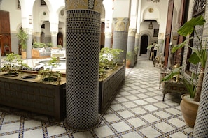 A courtyard with tiled flooring, columns, and potted plants. - Riad El Yacout (Fes)
