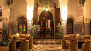 A lobby with a checkered floor, sofas, potted plants, and a central fountain. - Riad El Yacout (Fes)