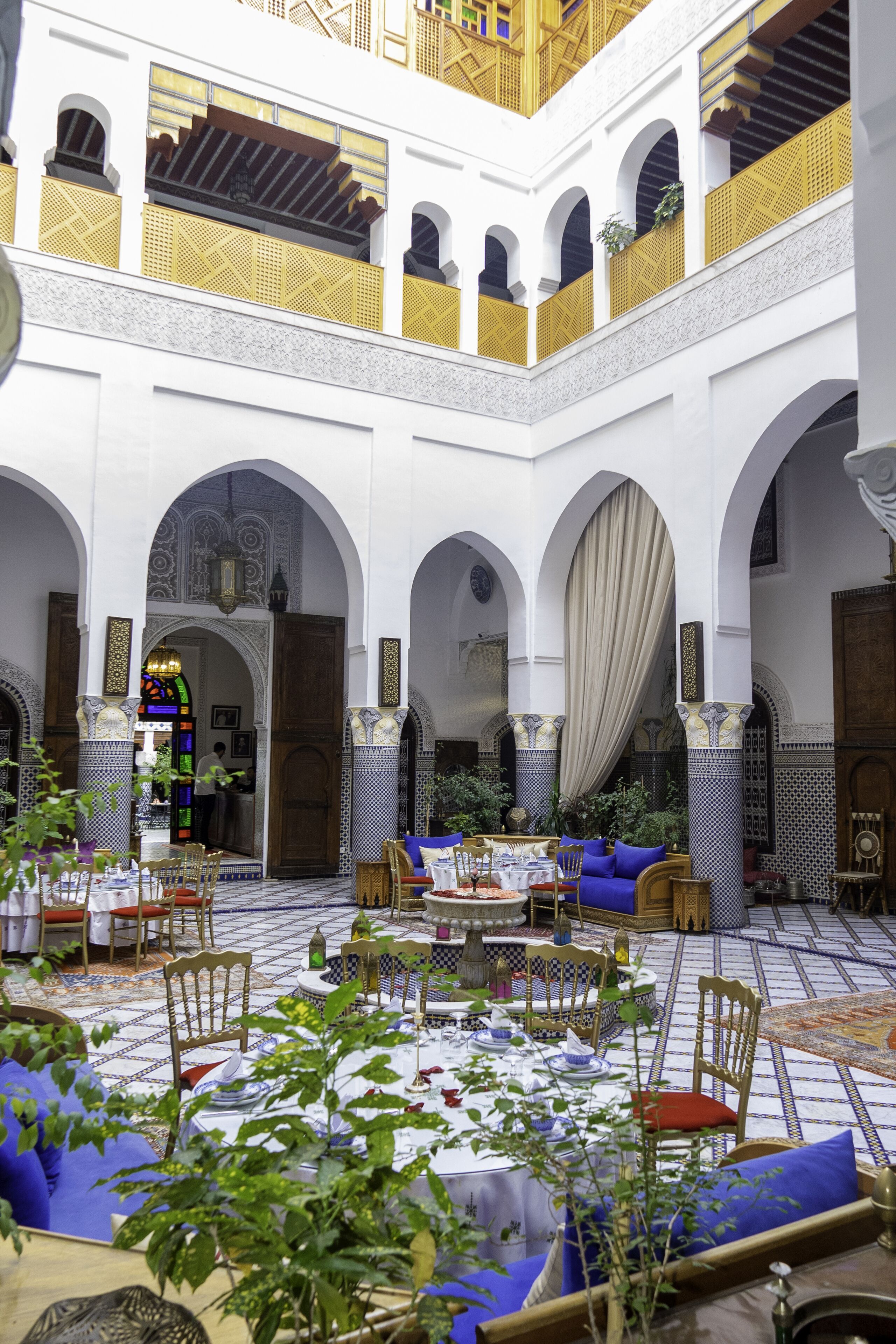 An interior courtyard with a dining area, arches, and a view of the outside.
