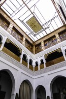Um interior em vários níveis com varandas arqueadas, um espaço central aberto e padrões intrincados no teto.