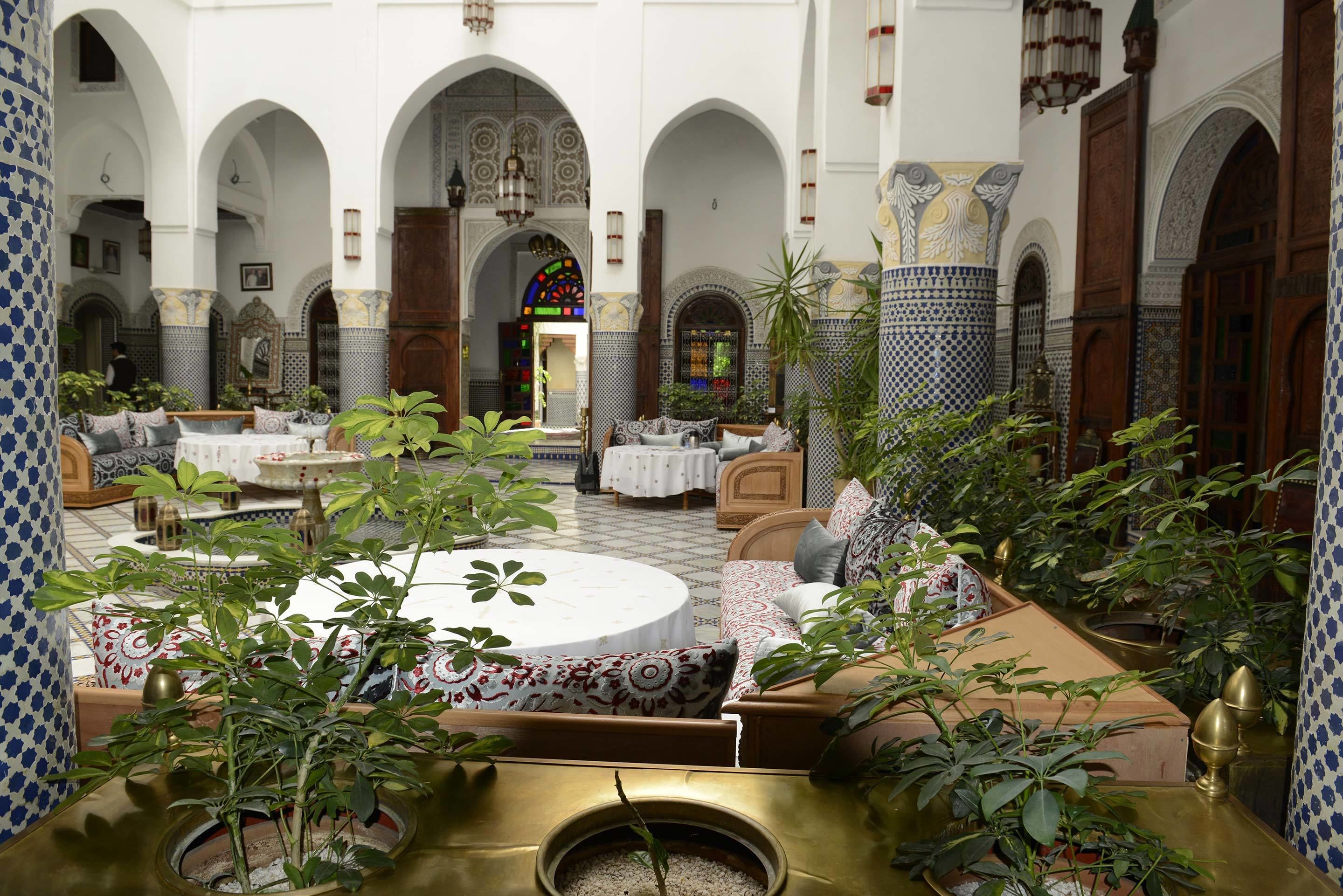 A courtyard with seating areas, a fountain, and a large window with intricate patterns.