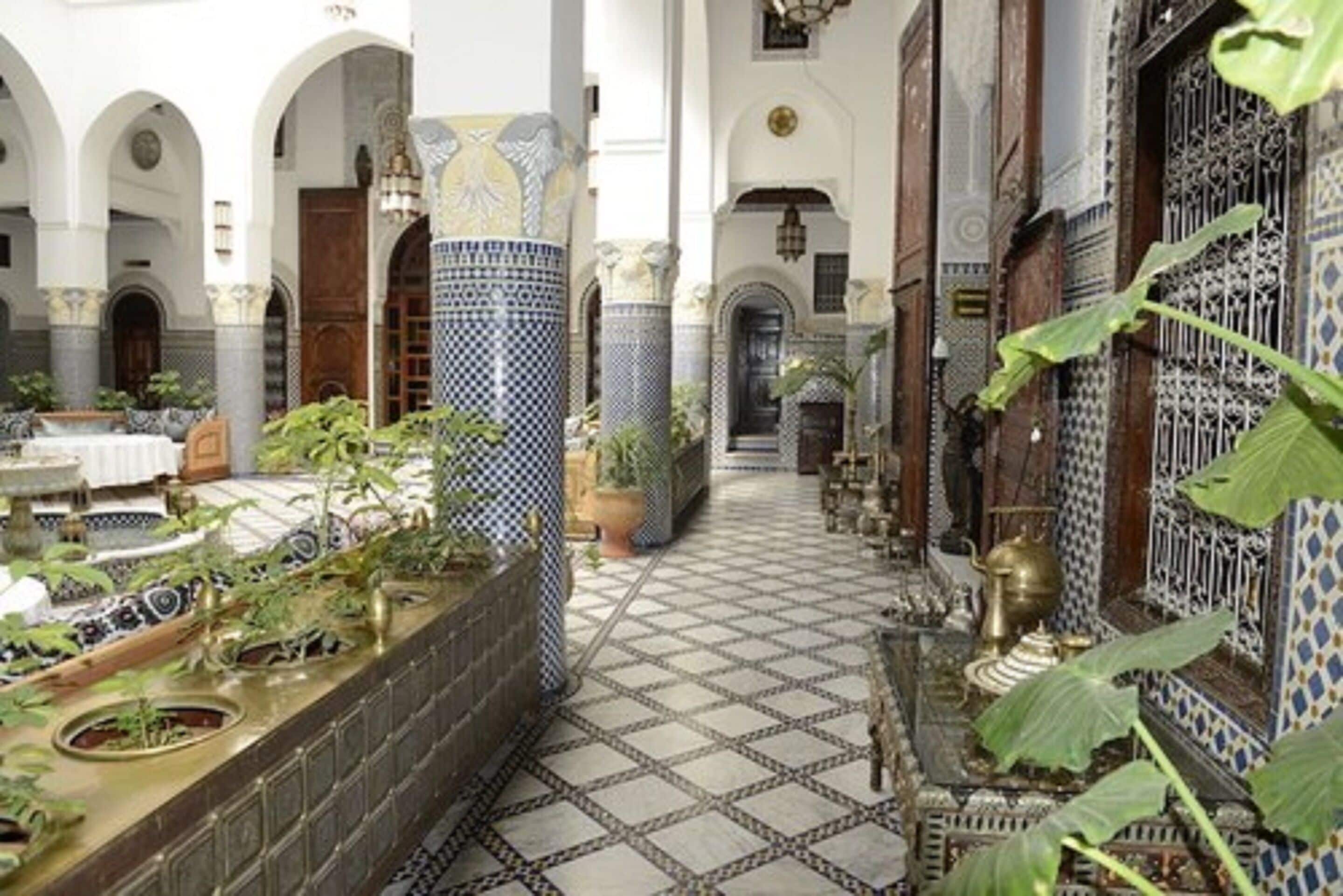 Un patio con suelo de baldosas, arcos y plantas en macetas.