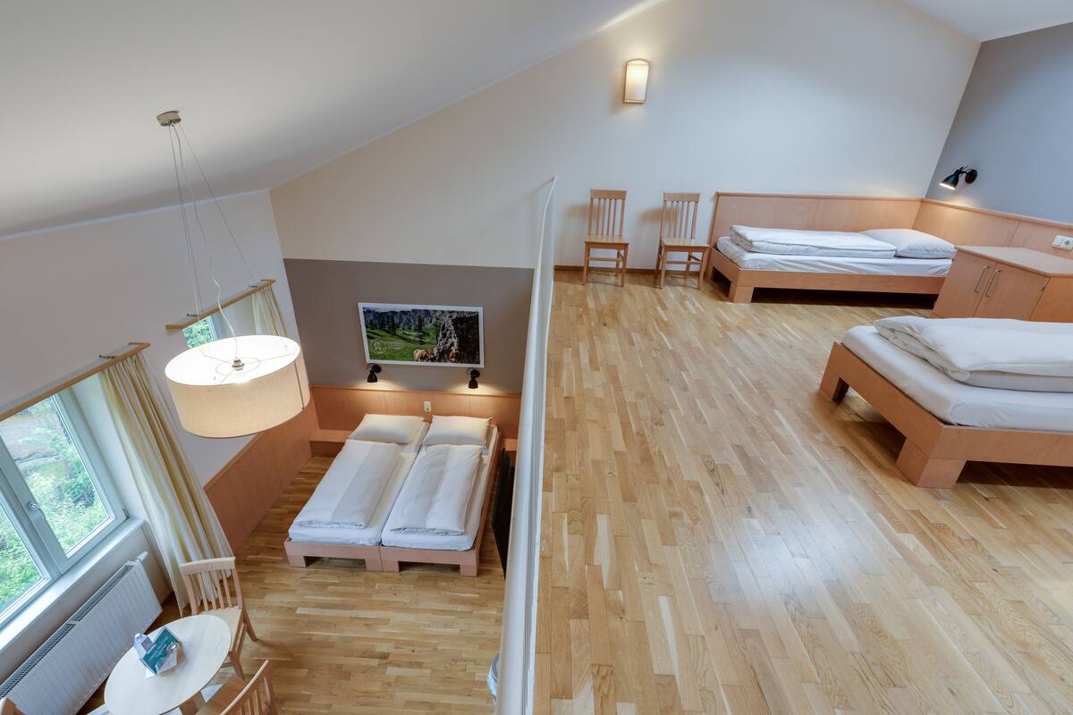 Een moderne, goed verlichte kamer met een groot raam, een bed, een bureau en een televisie.