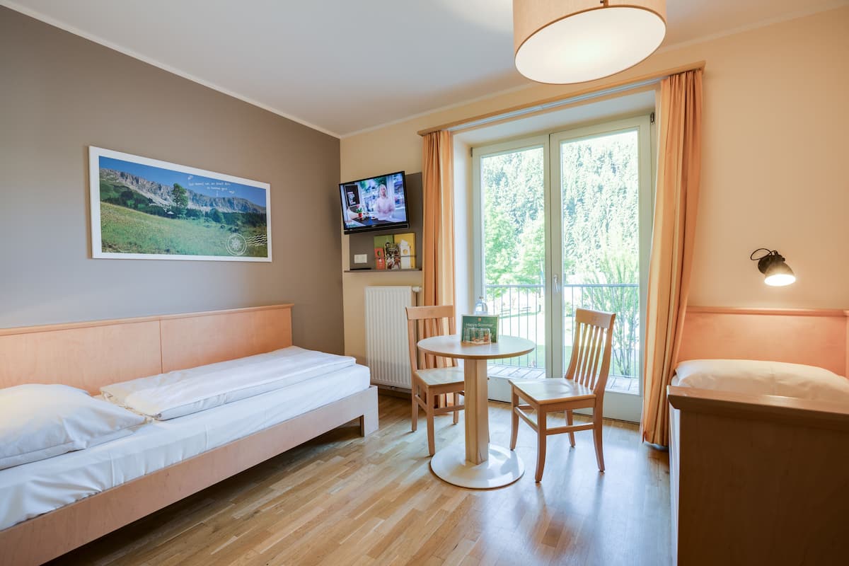 Een hotelkamer met een bed, een televisie, een tafel met stoelen en een raam met gordijnen.