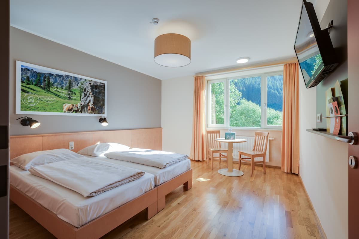 Een hotelkamer met een bed, bureau en televisie.