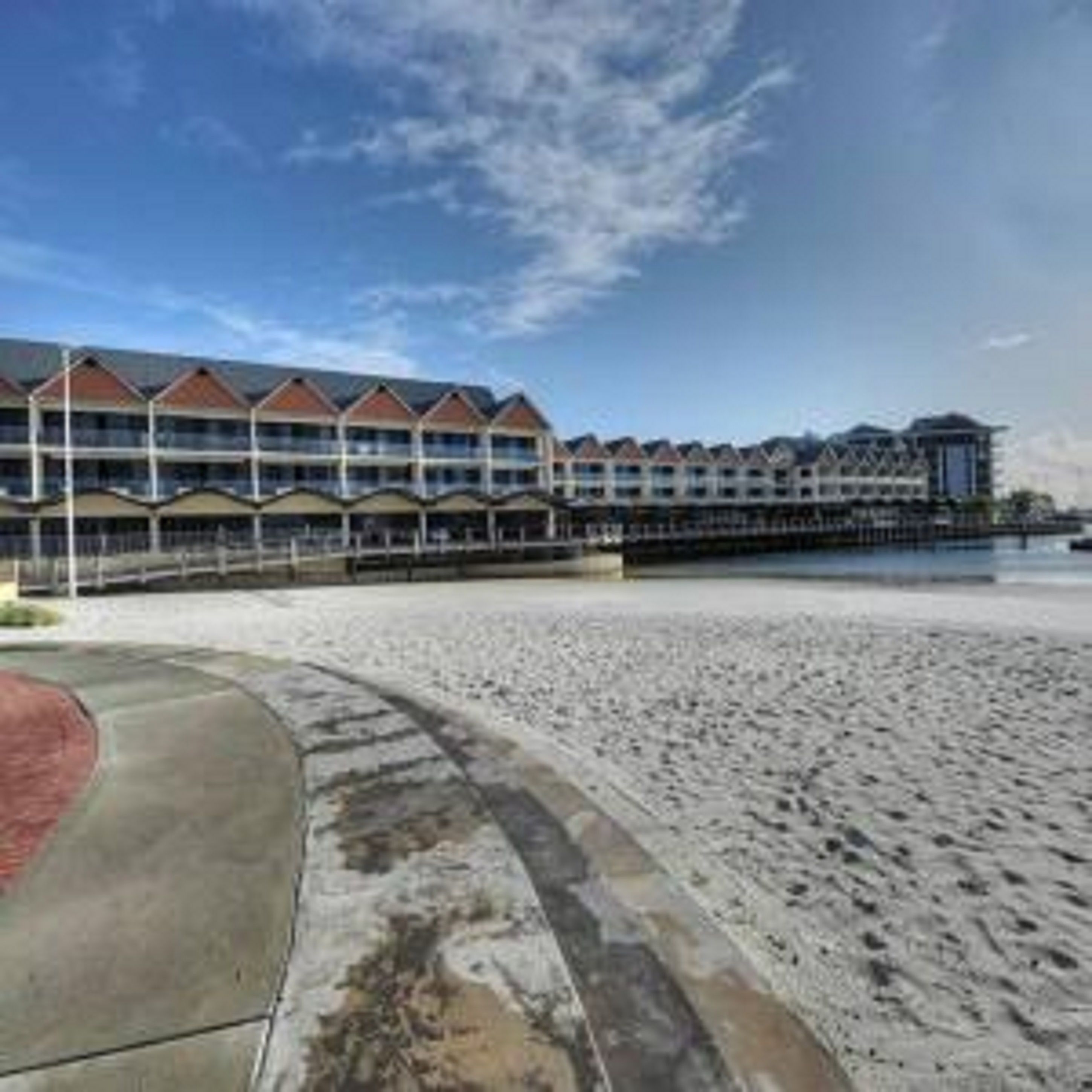 A beachfront hotel with a row of rooms overlooking the ocean.