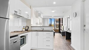 A modern kitchen with white cabinetry, stainless steel appliances, and a wooden countertop. - Dolphin Quay Apartments (Mandurah)