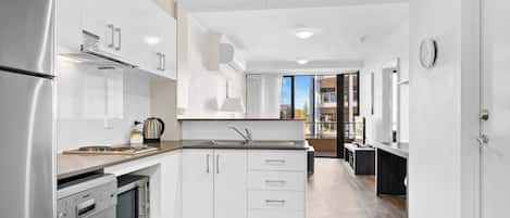 A modern kitchen with white cabinetry, stainless steel appliances, and a wooden countertop.