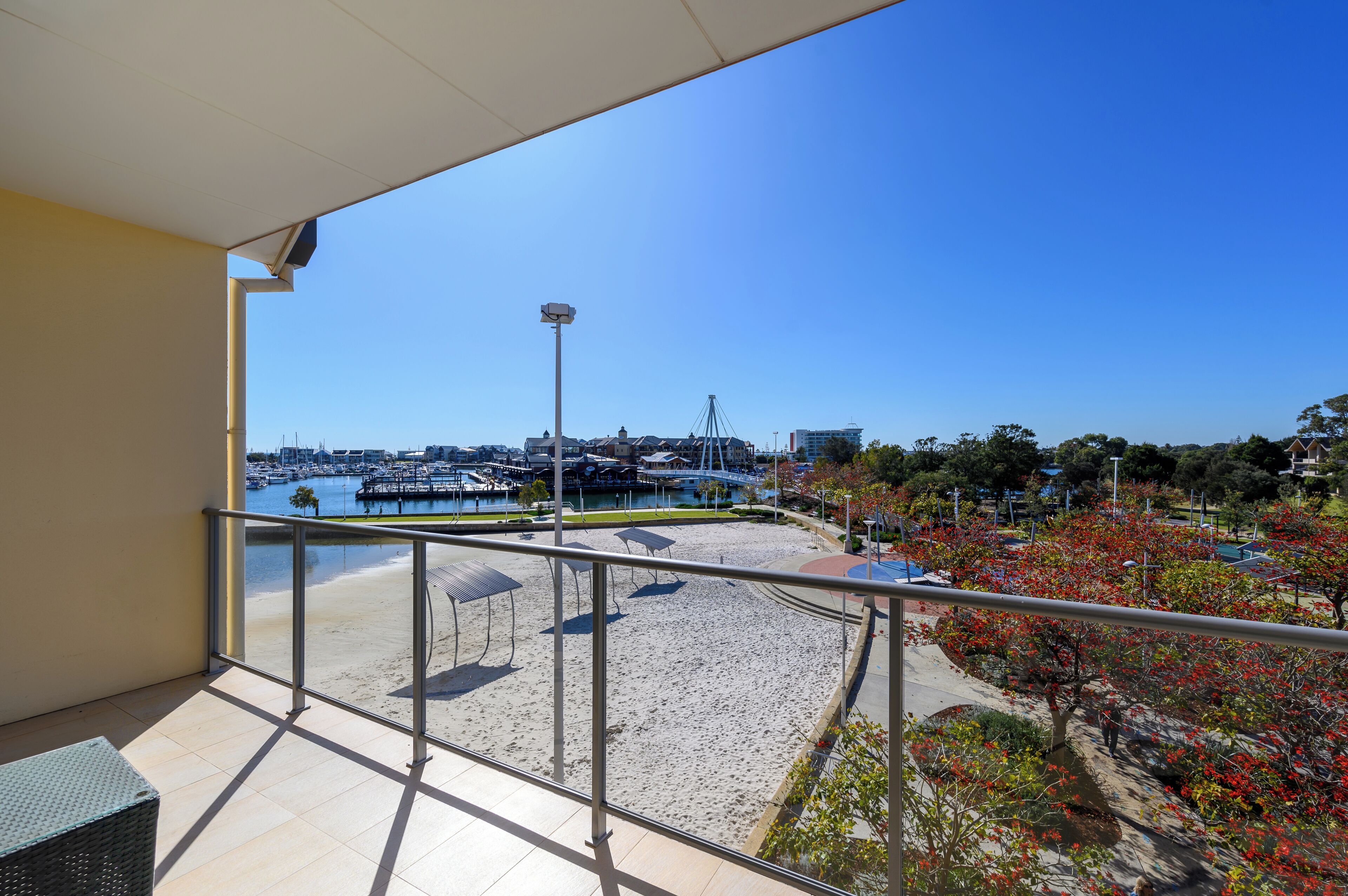 Een balkon met uitzicht op een jachthaven, strand en stadsbeeld.
