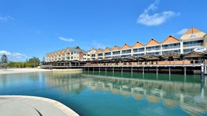A hotel with a row of rooms featuring a consistent architectural style, a waterfront view, and a covered outdoor area. - Dolphin Quay Apartments (Mandurah)