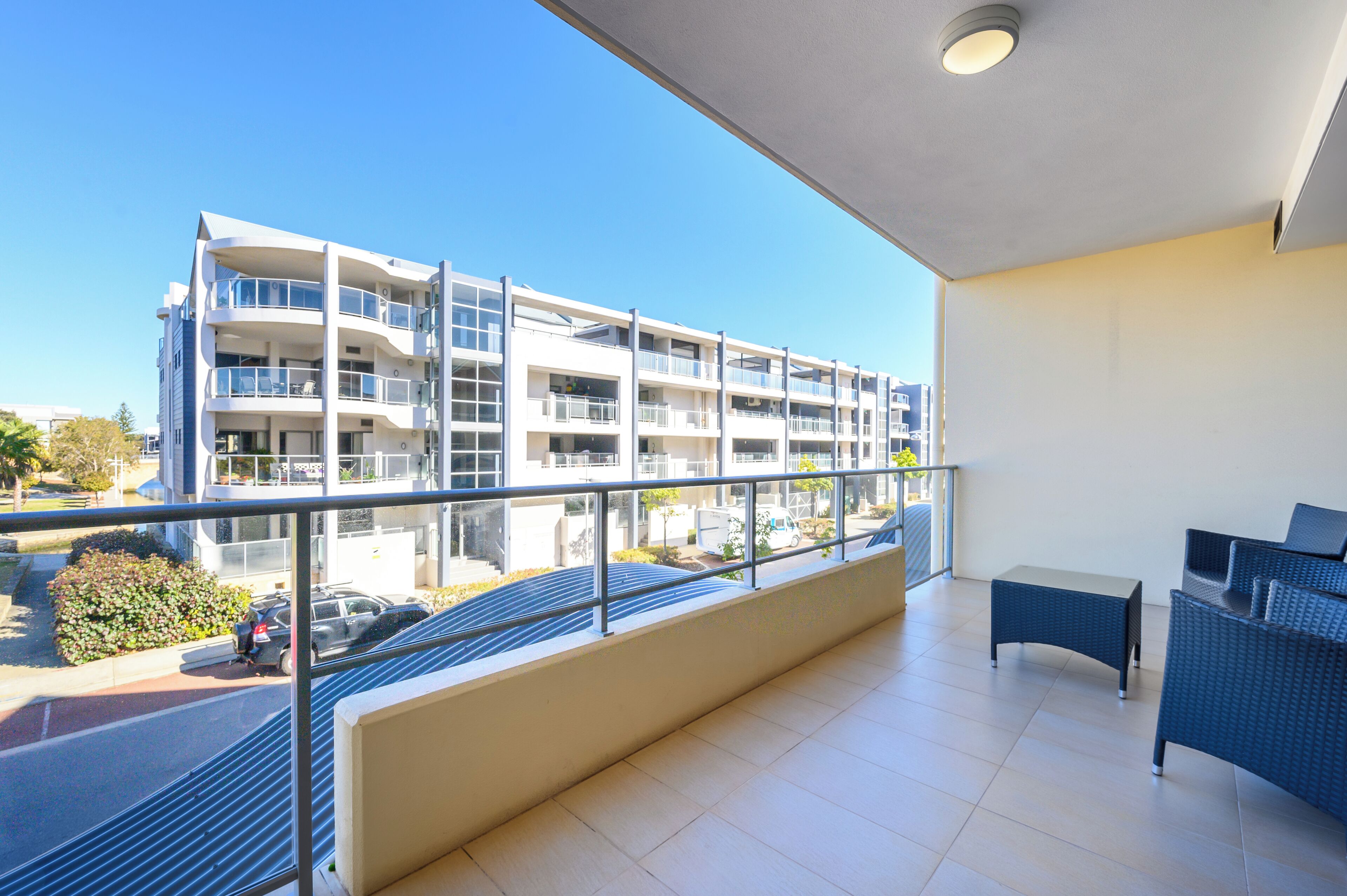 Un apartamento moderno con balcón, vistas a un edificio de varios pisos y un área de estar con mesa y sillas.