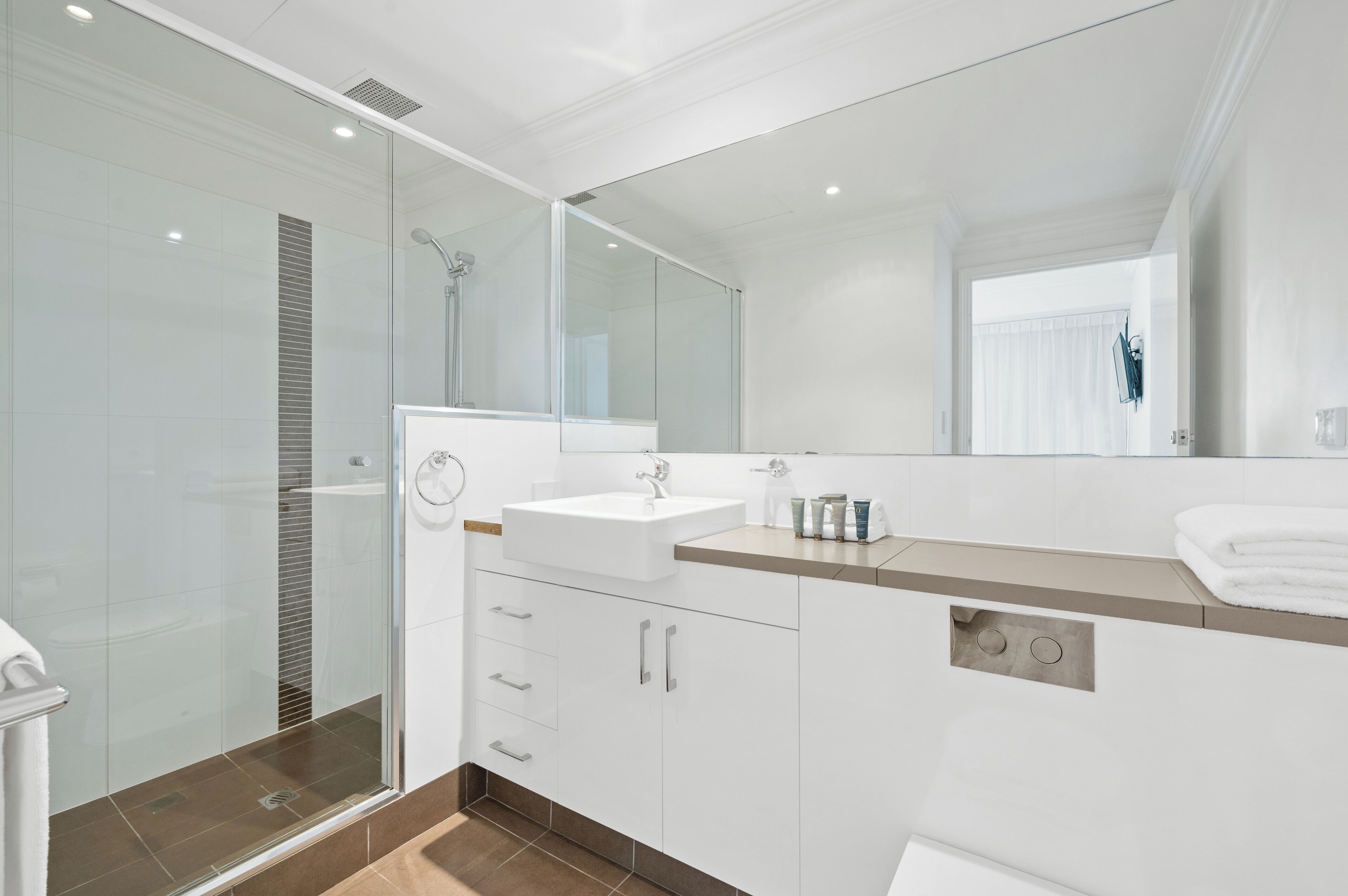 A modern bathroom with a glass shower enclosure, a sink with a vanity, and a large mirror.