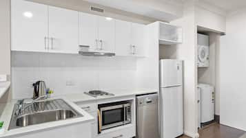 Una cocina moderna con armarios blancos, electrodomésticos de acero inoxidable y lavavajillas integrado.