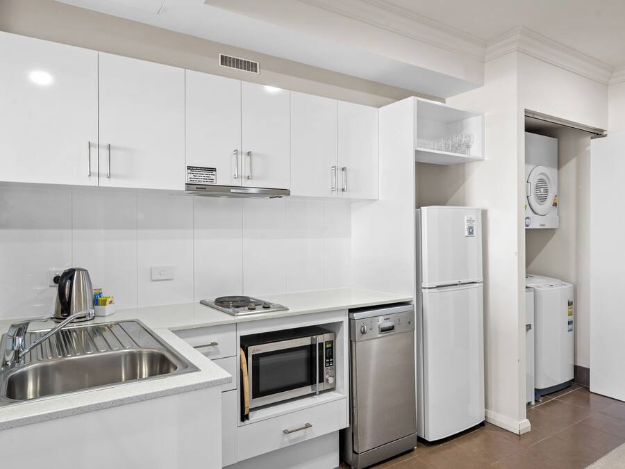 Una cocina moderna con armarios blancos, electrodomésticos de acero inoxidable y lavavajillas integrado.