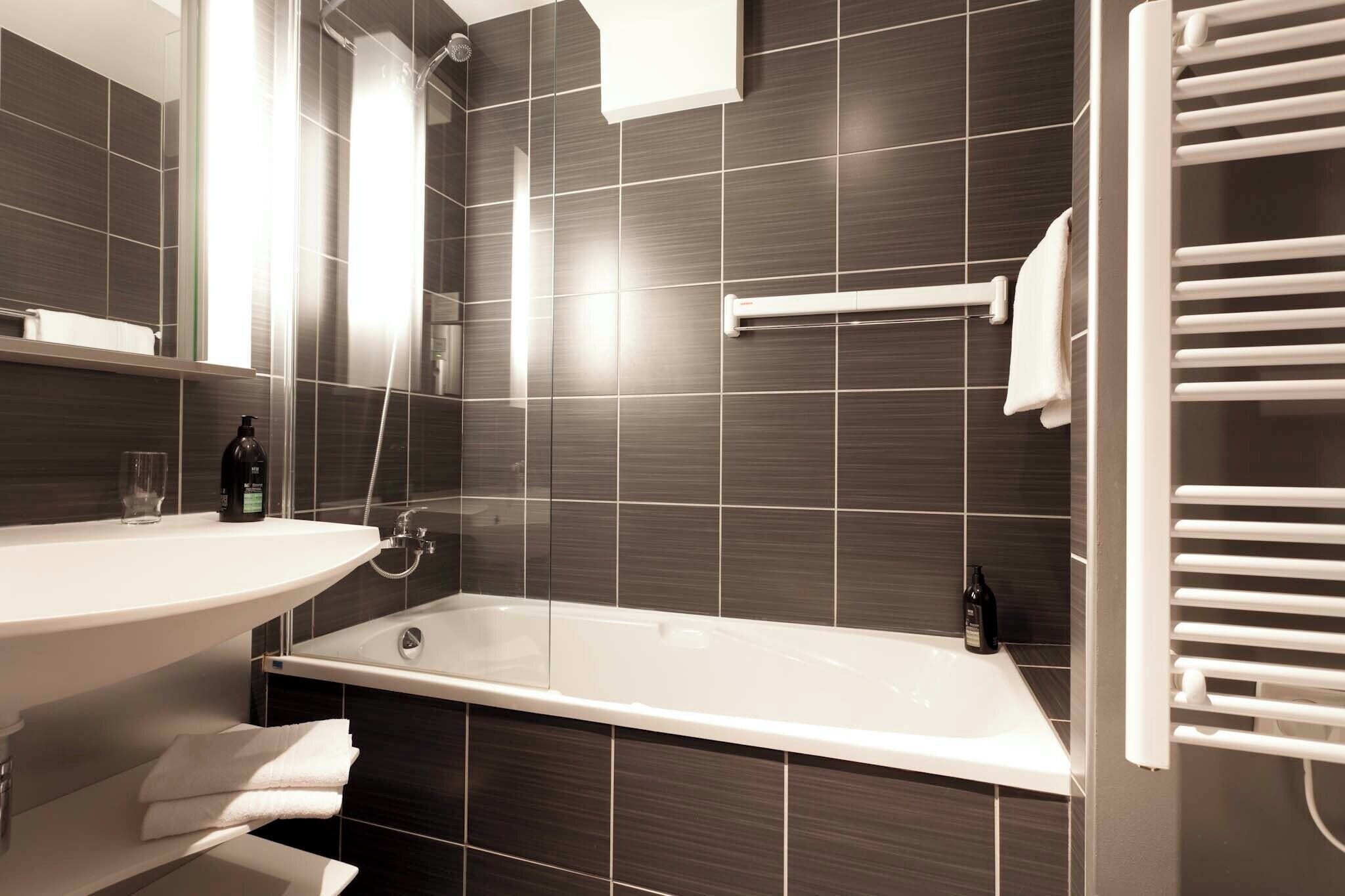 A modern bathroom with a bathtub, a sink, and a towel rack.