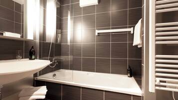 A modern bathroom with a bathtub, a sink, and a towel rack.