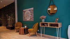 A modern reception area with teal walls, a large abstract artwork, and a round mirror.