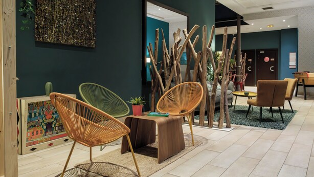 A modern lounge area with wicker chairs, a wooden table, and a unique wooden sculpture.