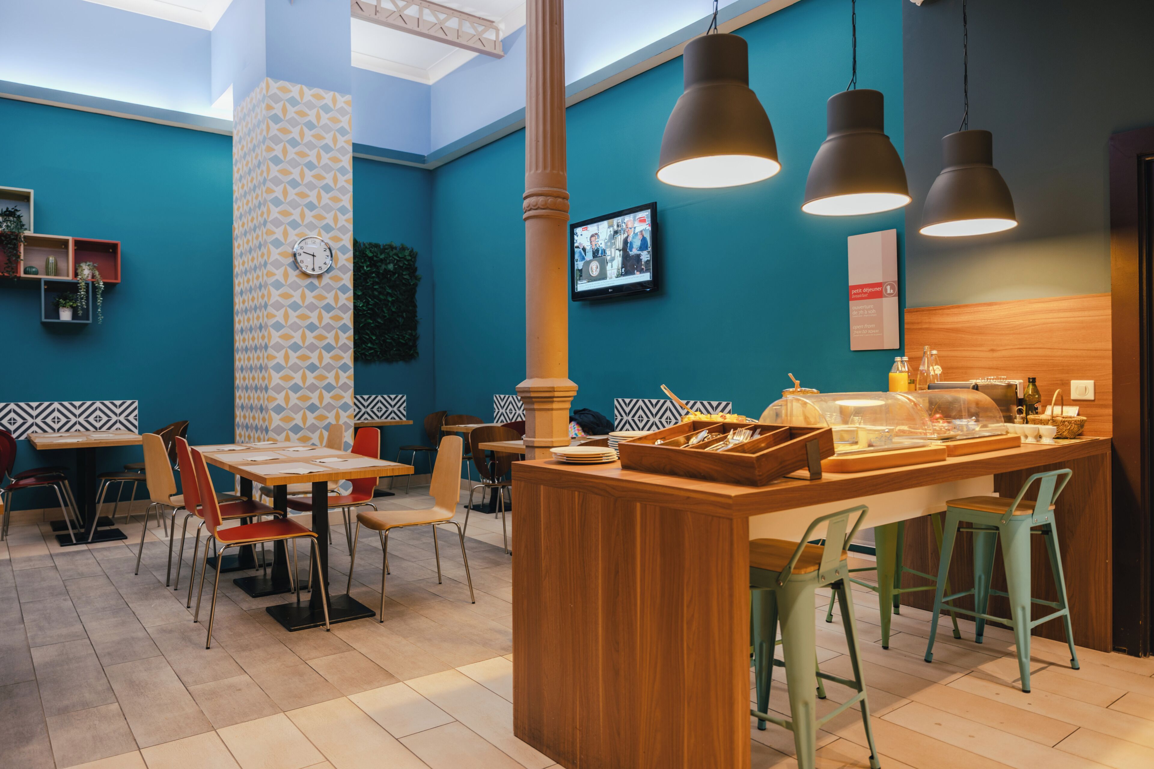 A restaurant interior with a central bar area, multiple tables, chairs, and hanging pendant lights.