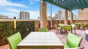 Un patio al aire libre con mesas y sillas, una pérgola y vistas a la ciudad.