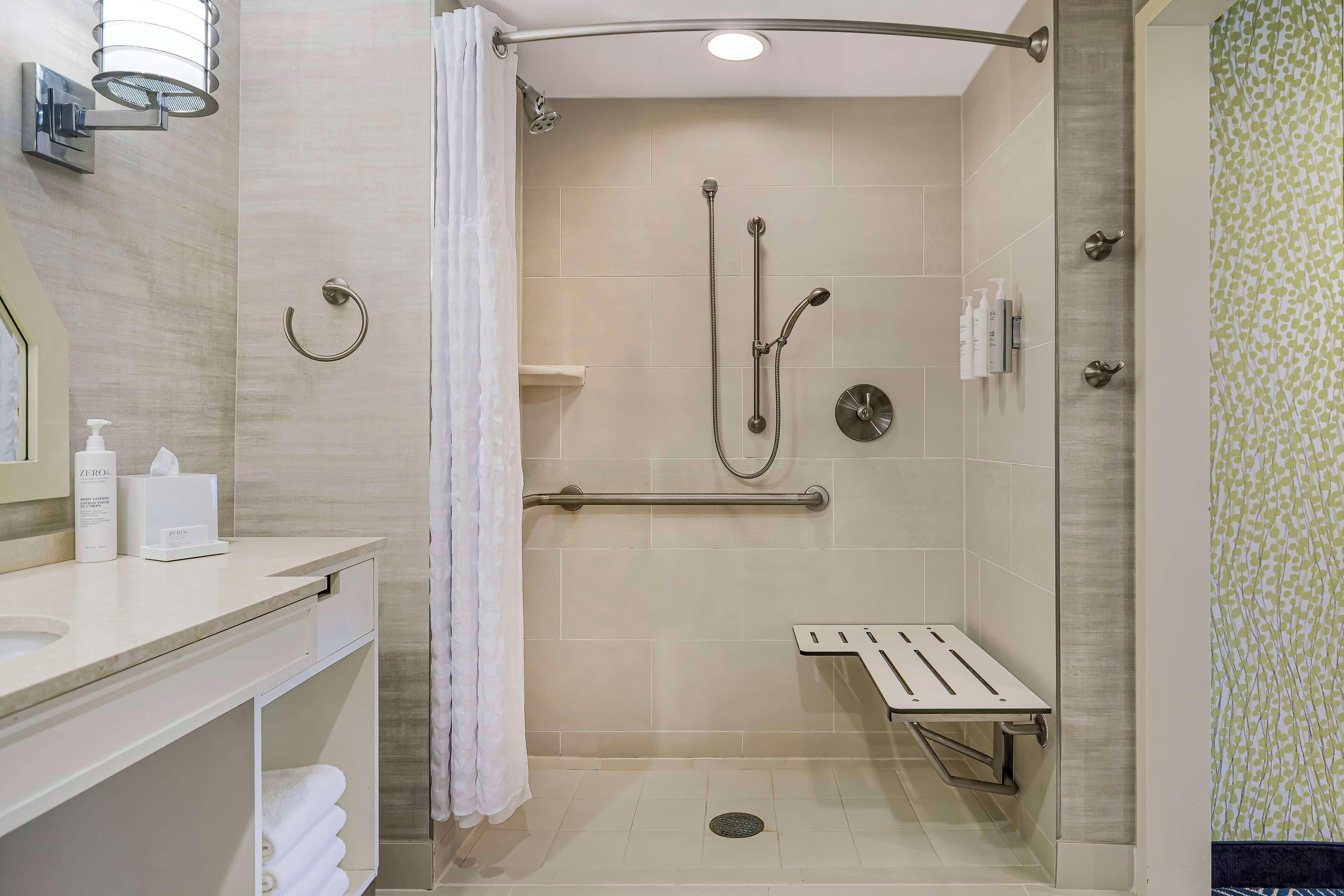 Un baño moderno con ducha, tocador con espejo y retrete.