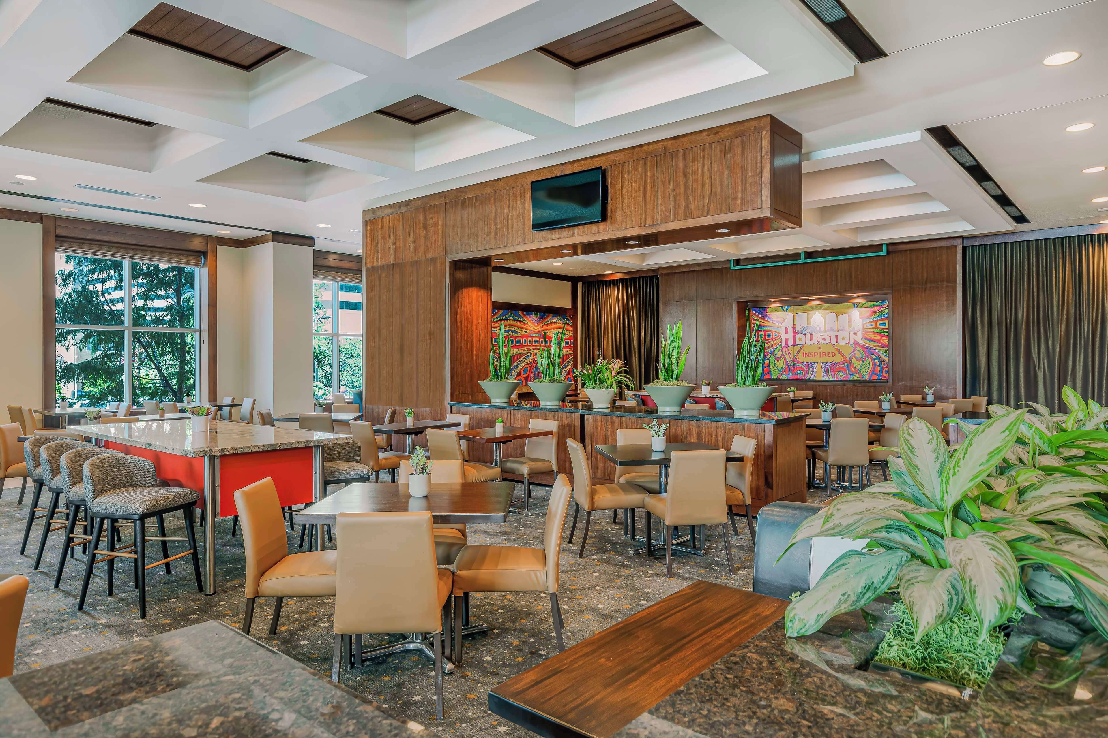 A modern restaurant with a bar area, multiple seating options, and large windows.
