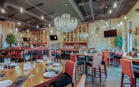 A restaurant with multiple dining tables, chairs, and a large chandelier.