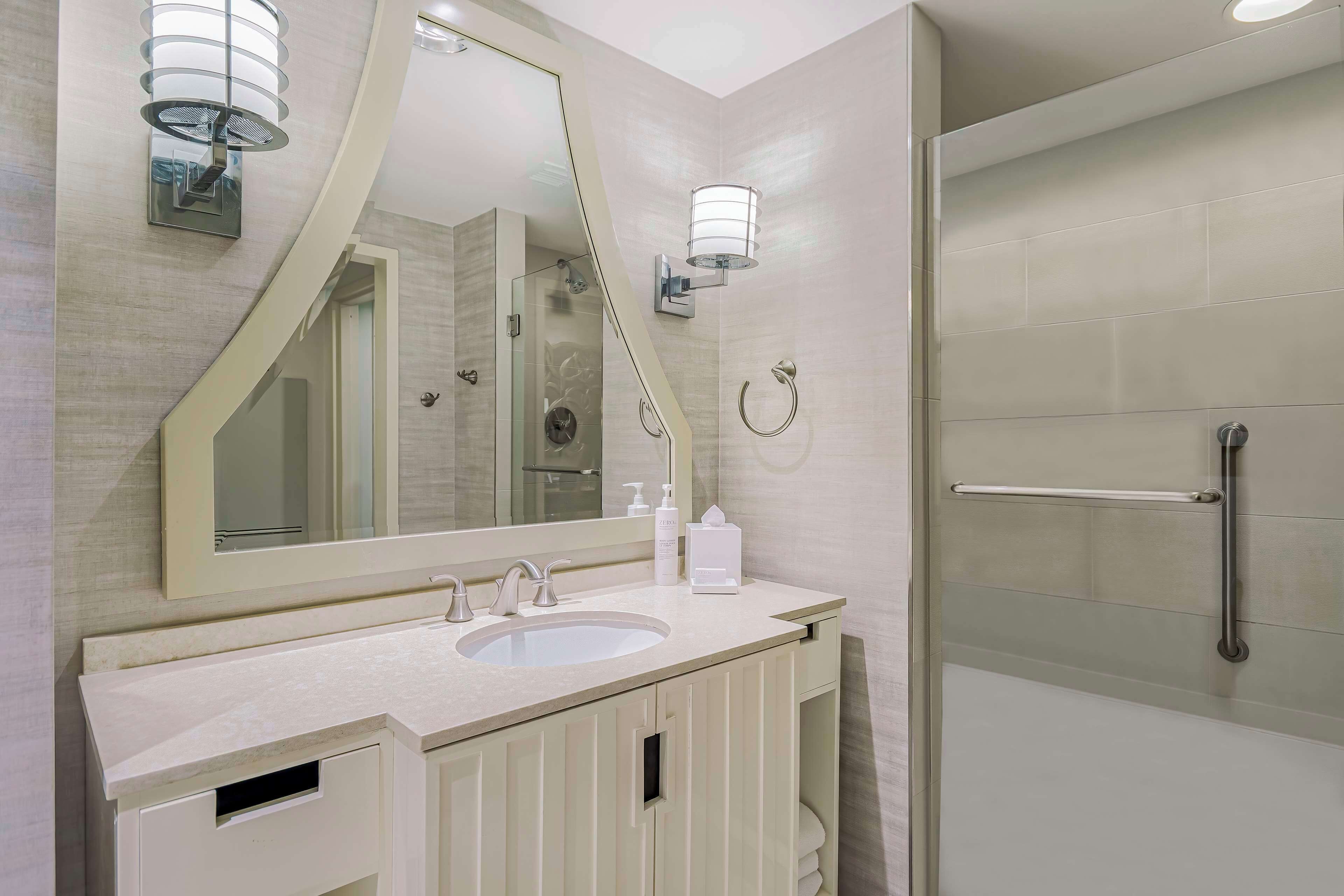 Un baño moderno con un espejo grande, un lavabo y una ducha.