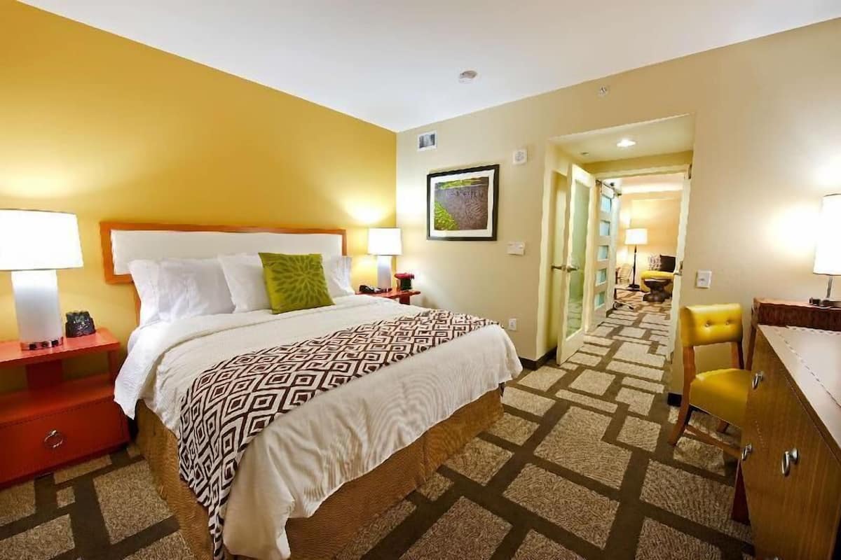 A hotel room with a bed, bedside tables, a desk, and a chair.