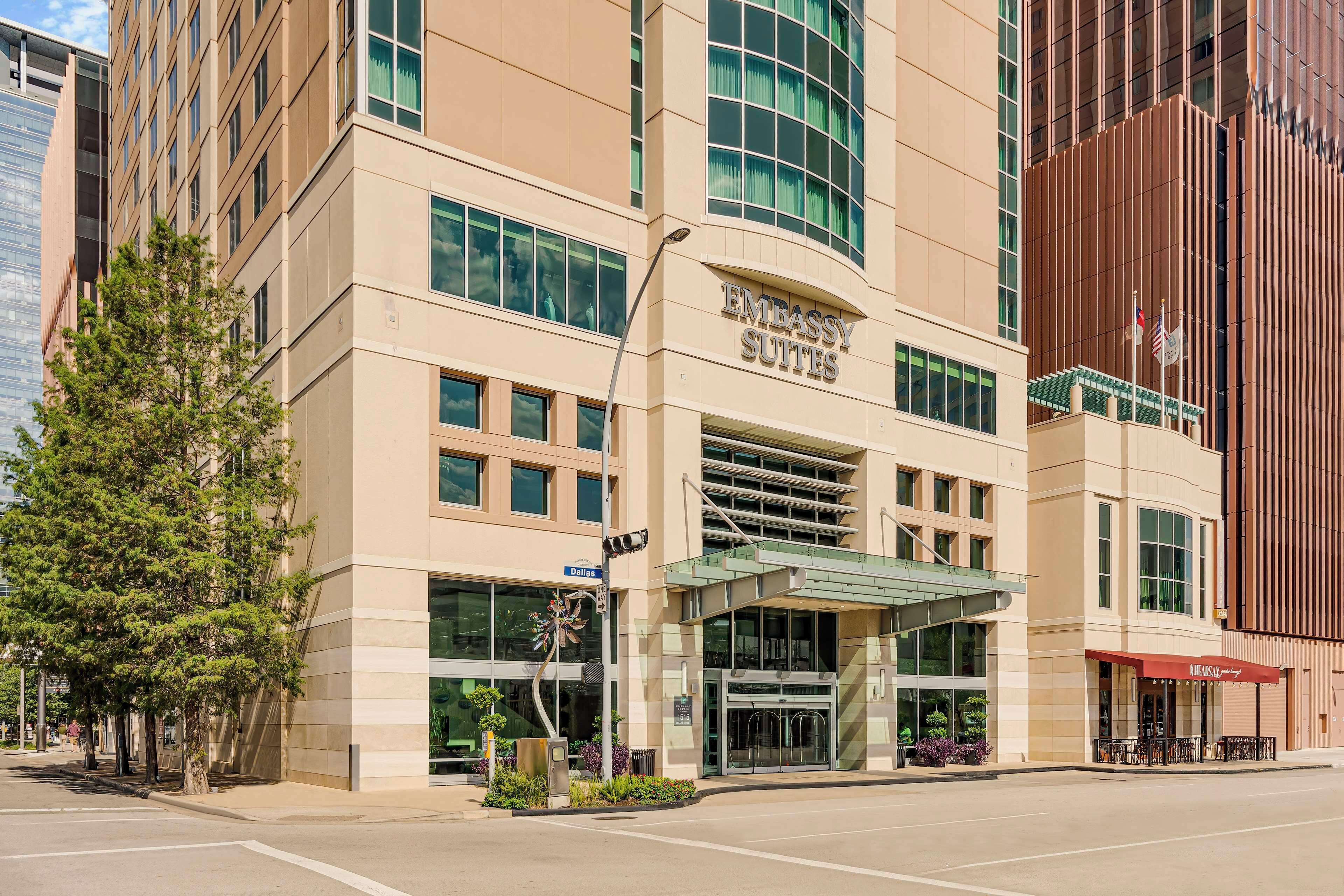 A modern building with 'Embassy Suites' signage, large windows, and a covered entrance.